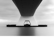 Symmetrisch zicht vanonder het betonnen dek van de Zeelandbrug op een witte pijler die in glad, zilvergrijs water staat.