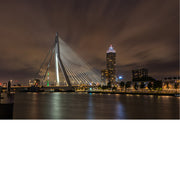 Verlichte Erasmusbrug en de skyline van Rotterdam weerspiegelen in de rivier onder een warm gekleurde nachtelijke wolkenlucht.