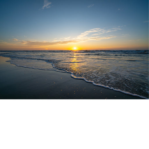 Een weids uitzicht over de zee tijdens zonsondergang. De zachte golven rollen over het natte zand en reflecteren de gouden lucht.