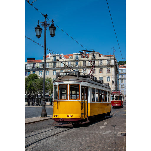 Een iconisch beeld van een felgele tram in een Europese stad, rijdend door een straat met oude, karaktervolle gebouwen onder een strakblauwe lucht.