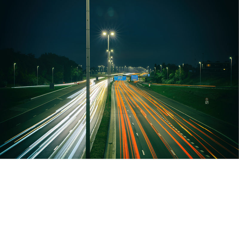De A12 tijdens het spitsuur. Gefotografeerd tijdens het blauwe uurtje na zonsondergang. De lichtstrepen van de auto's geven de drukte weer op de autosnelweg. De verlichting geeft iets feeërieks aan de drukte.