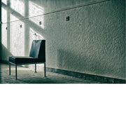 Ruimte in een verlaten pand met zwarte vintage zetel gericht naar het lichtrijke raam