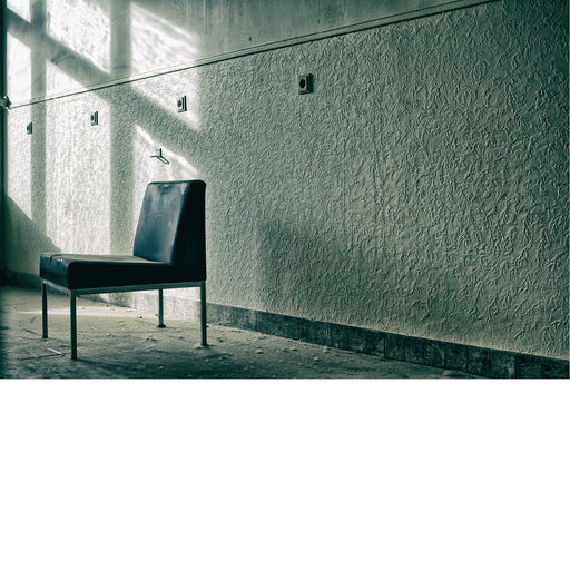 Ruimte in een verlaten pand met zwarte vintage zetel gericht naar het lichtrijke raam