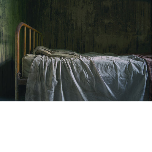 Traliebed met laken vol kreuken en plooien. Foto met knipoog naar de Vlaamse primitieven zoals Van Eyck