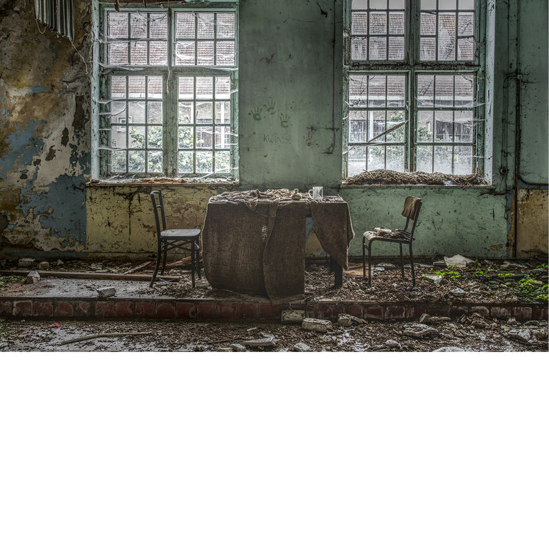 Kleine theaterruimte in zwaar vervallen staat met daarin een tafel en twee stoelen  