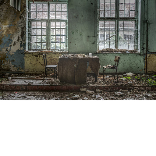 Kleine theaterruimte in zwaar vervallen staat met daarin een tafel en twee stoelen  