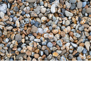 Close-up van talrijke gekleurde kiezelstenen in bruin-, grijs- en okertinten op het strand.