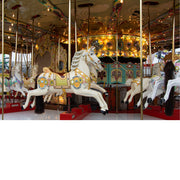 Wit paard met sierlijk beschilderde tuigage springt op een verlichte kermiscarrousel, met gouden lampjes op de achtergrond.