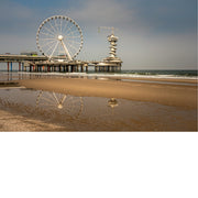 Pier van Scheveningen met reuzenrad weerspiegelt in een ondiepe plas op het natte strand.