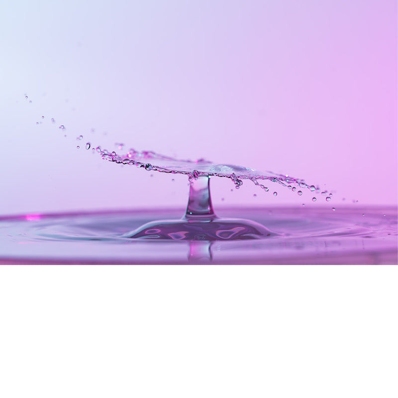 macro-opname van 2 druppels water die op elkaar botsen in roze tinten