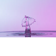 macro-opname van 2 druppels water die op elkaar botsen in roze tinten