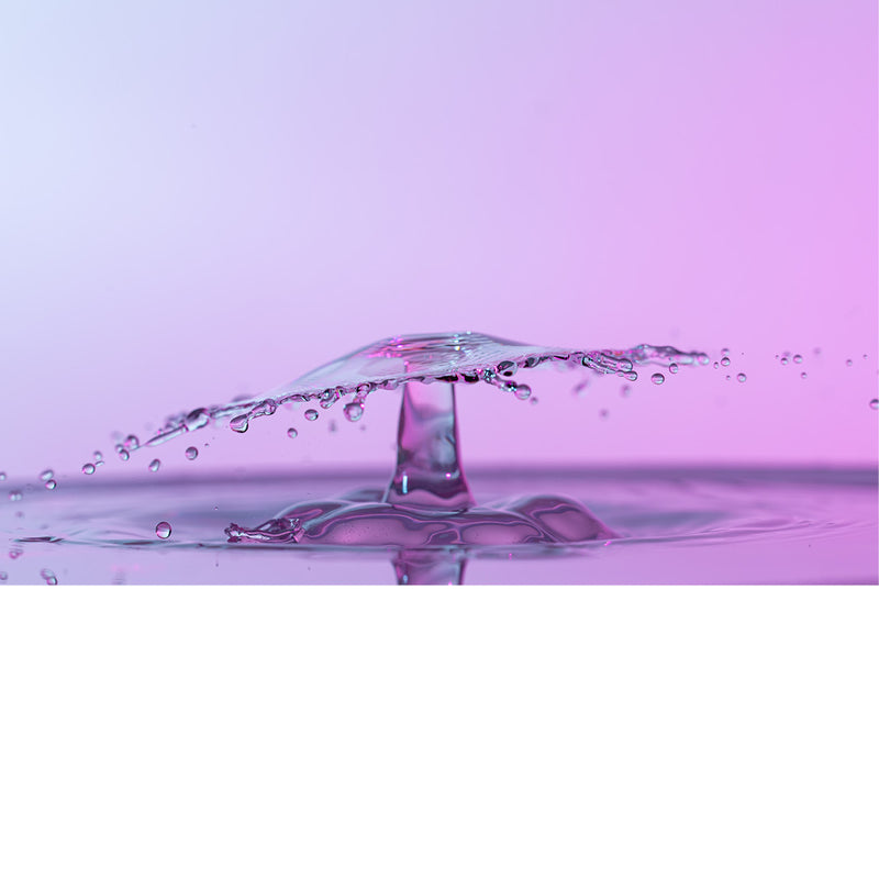 macro-opname van 2 druppels water die op elkaar botsen in roze tinten