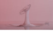 macro-opname van 2 druppels water die op elkaar botsen in melk in roze tinten