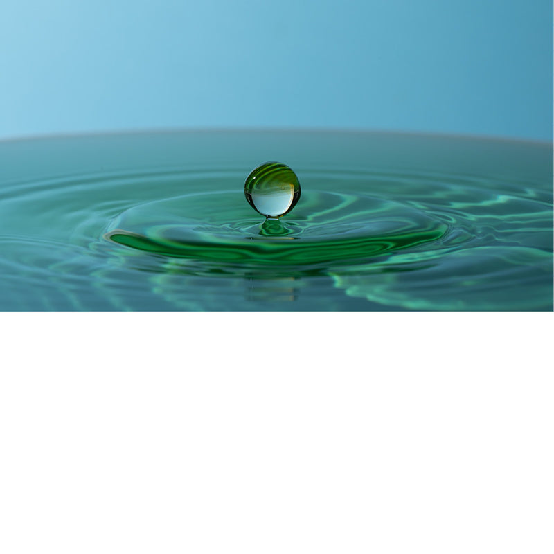 macro-opname van een vallende druppel in blauw met groene tinten