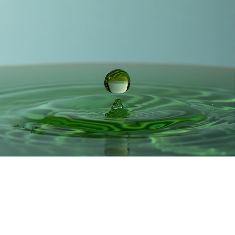 macro-opname van een vallende druppel in blauw met groene tinten