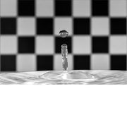 macro-opname van een waterdruppel op het moment van impact met reflectie in druppel van zwart met wit geblokte achtergrond