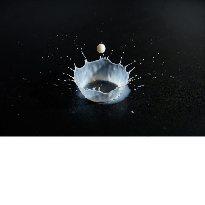 macro-opname van druppel melk vallend op zwarte ondergrond