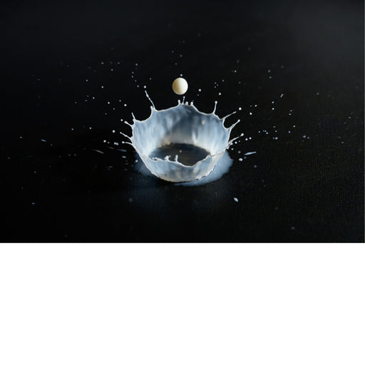 macro-opname van druppel melk vallend op zwarte ondergrond