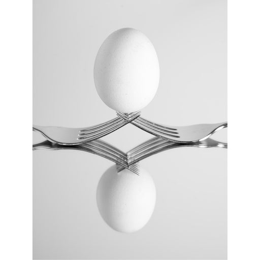 macro-opname van de reflectie van een wit ei geposeerd op 2 vorken op een spiegel