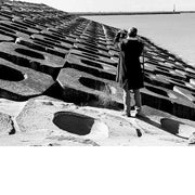 Foto van een man die een foto maakt van de Pier van Oostende, staand op golfbrekers.