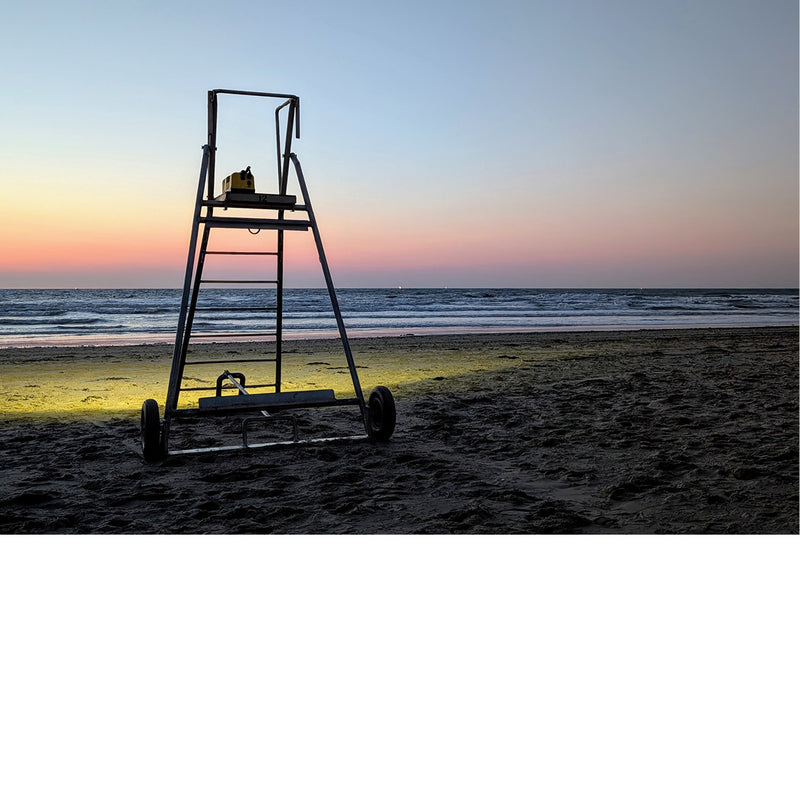 Vlak na zonsondergang geeft een licht op een reddersstoel en uitzonderlijk kleurenspel op het strand.