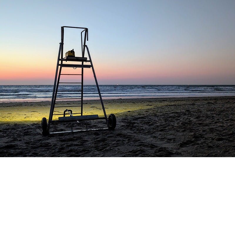 Vlak na zonsondergang geeft een licht op een reddersstoel en uitzonderlijk kleurenspel op het strand.