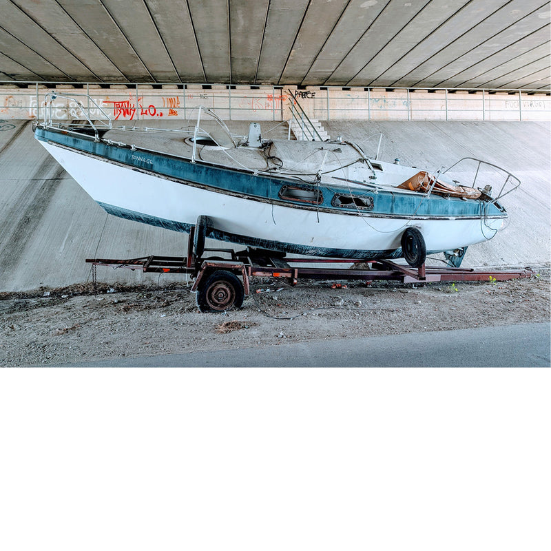 Onder een brug staat een versleten bootje fout geparkeerd.
