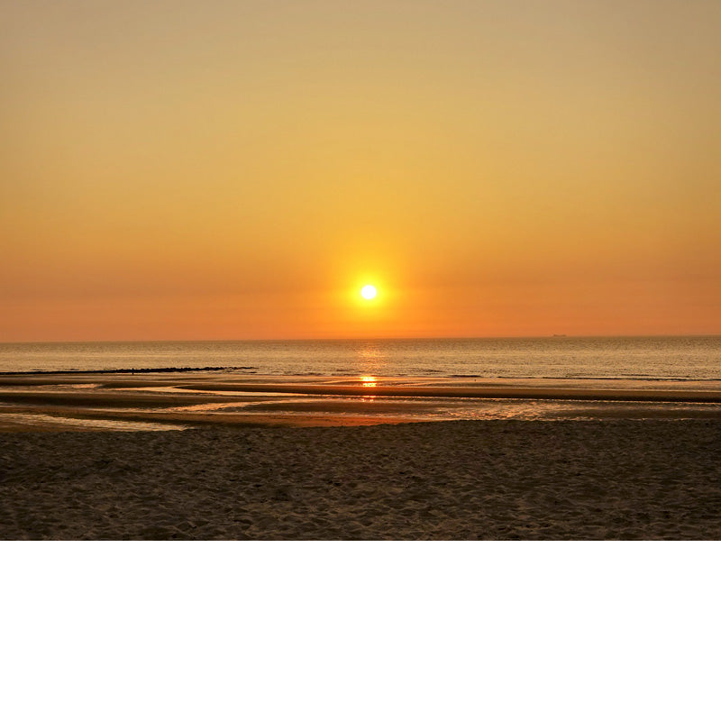 Een warme zonsondergang met reflecties in het zeewater.