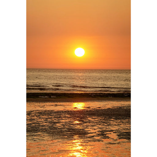 Een warme zonsondergang met reflecties in het zeewater.