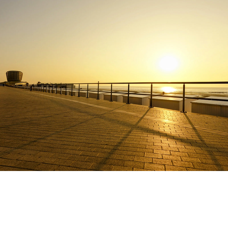 De ondergaande zon werpt schaduwlijnen op de dijk, het casino van Middelkerke op de achtergrond.