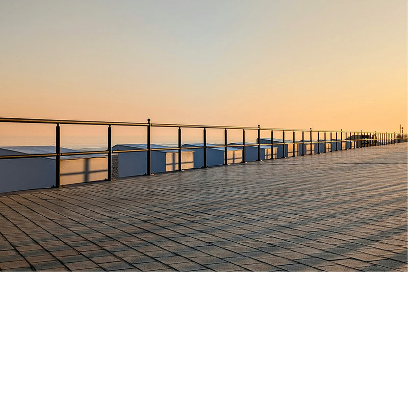 De opkomende zon werpt schaduwkruisen op de strandcabines.