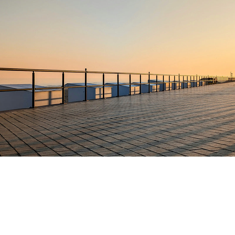De opkomende zon werpt schaduwkruisen op de strandcabines.