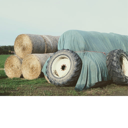 De ingehaalde hooibalen worden afgedekt met een zeil en vastgezet met oude tractorbanden.