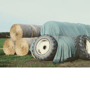 De ingehaalde hooibalen worden afgedekt met een zeil en vastgezet met oude tractorbanden.