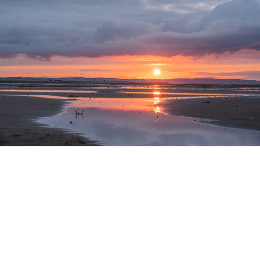 Deze zonsondergang is fantastisch. Een warme gloed met daarboven intense wolken en onderaan reflecties op het strand.