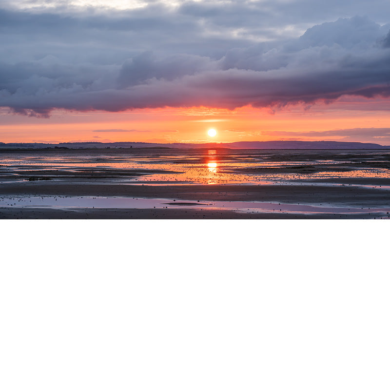 Deze zonsondergang is fantastisch. Een warme gloed met daarboven intense wolken en onderaan reflecties op het strand.