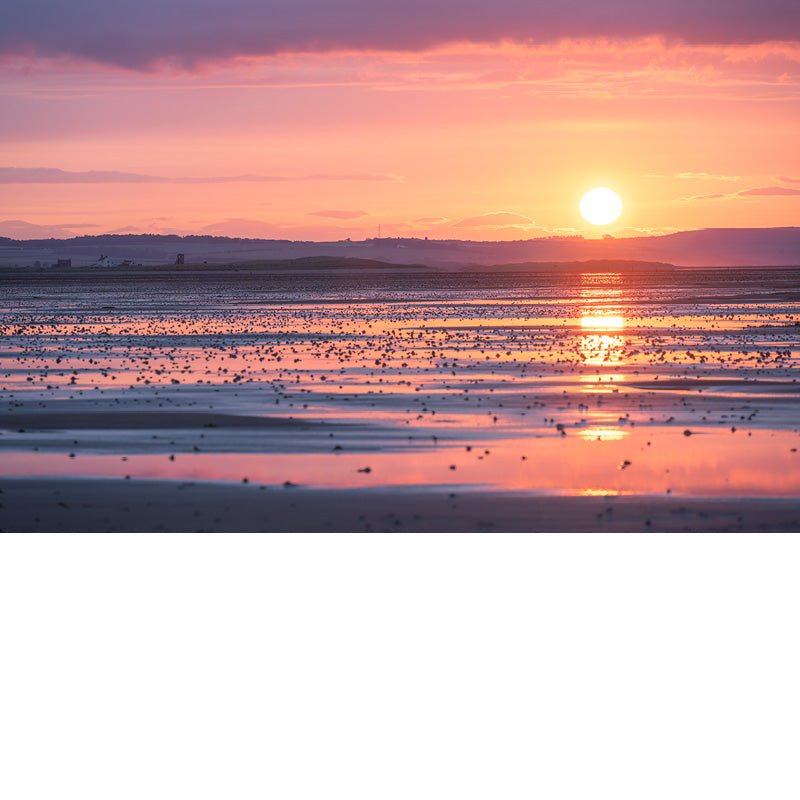 Deze zonsondergang is fantastisch. Een warme gloed met daarboven intense wolken en onderaan reflecties op het strand.