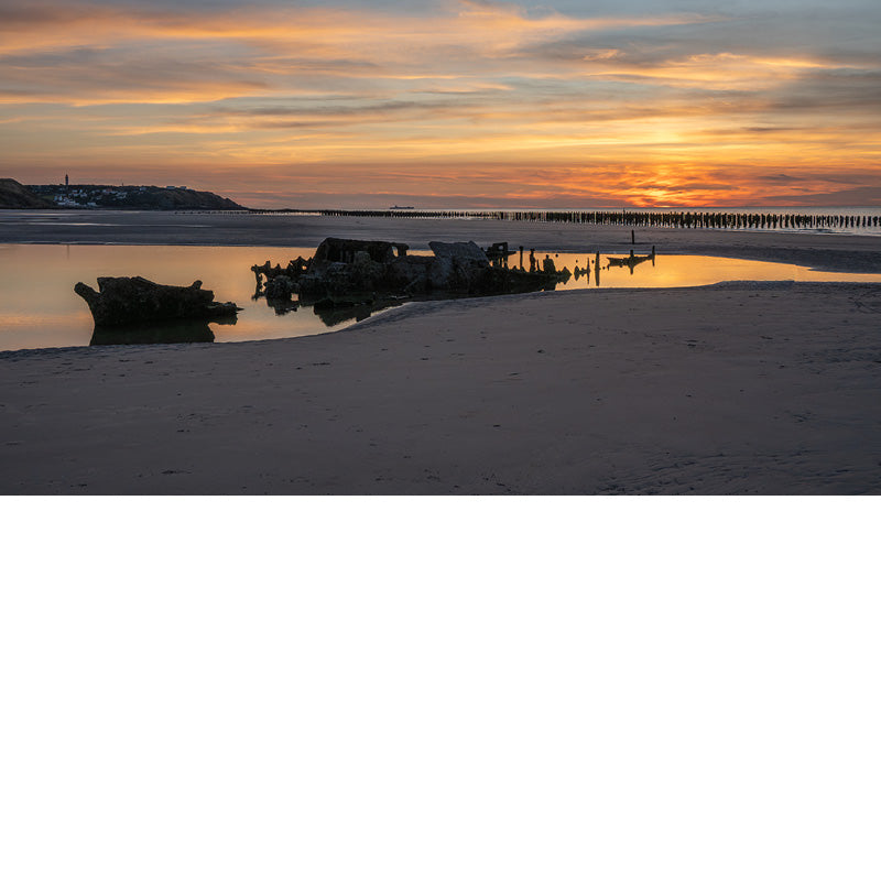 Sfeervolle blik op het strand met de zon die net verdwenen is, maar de lucht nog kleurt.