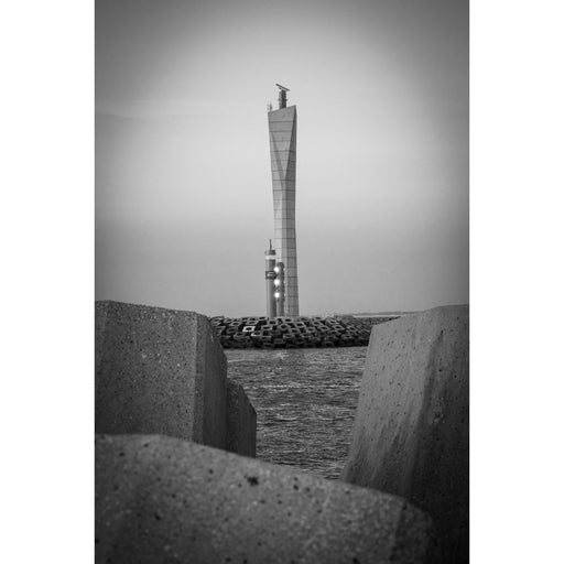 Gedraaide radartoren aan de haven van Oostende, ingekaderd tussen twee betonblokken met het water ertussen.