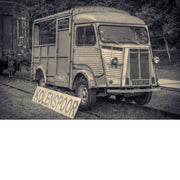 Verweerde oude Citroën-bestelwagen op de sporen bij het oude stationnetje van As, met een bord Kolenspoor en een roestige treinwagon ernaast.