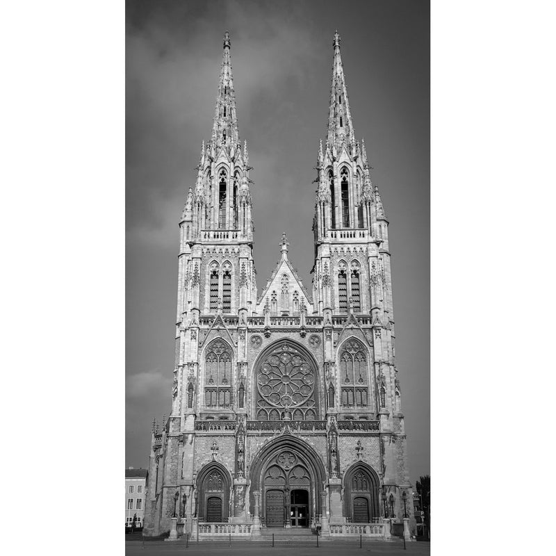 Frontaal zicht op de neogotische Sint-Petrus-en-Pauluskerk in Oostende, met twee rijk versierde spitse torens en een groot roosvenster onder een grijze lucht.