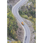 Een geel busje rijdt op een bergweg in Montenegro