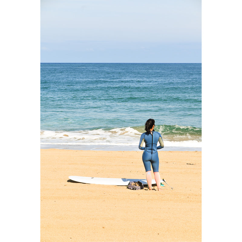 Een vrouw met een surfplank staat op het strand