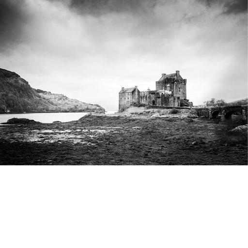 Kasteel Eilean Donan ligt bij laag water aan het loch, met de oude stenen brug en de heuvels van de Schotse Highlands op de achtergrond.
