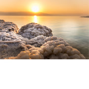 Op de rotsen liggen zoutafzettingen, terwijl de zon ondergaat aan de Dode Zee.