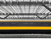 Een trein rijdt door een station, met een focus op het dak van het station en de sporen.