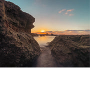 Een zonsondergang bij de kust, met een ruige kustlijn en panoramisch uitzicht. 