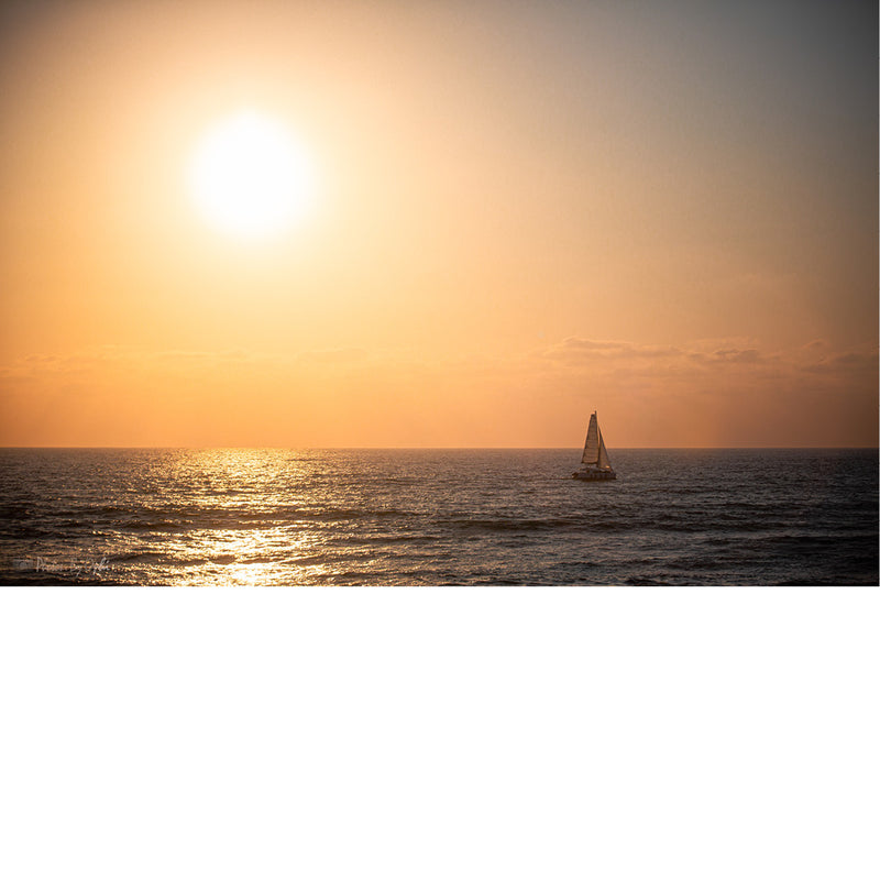 Een zeilboot op zee bij zonsondergang.