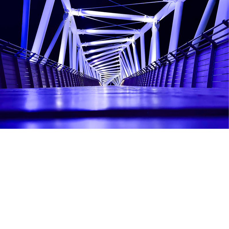De HaShmurot-brug in Netanya, Israël. Het is een voetgangers- en fietsbrug die 's nachts wordt verlicht met blauwe led-verlichting.