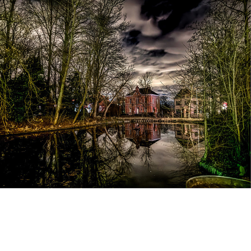 Het August De Boeckhuis in Merchtem wordt weerspiegeld in de Kerkvijver.